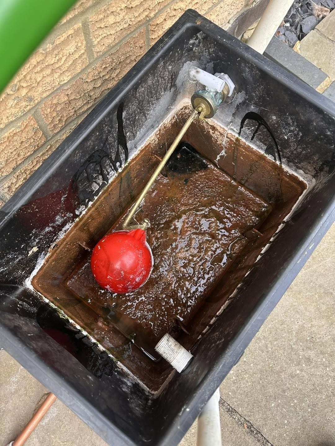 A dirty cold water storage cistern with its ball valve, before cleaning