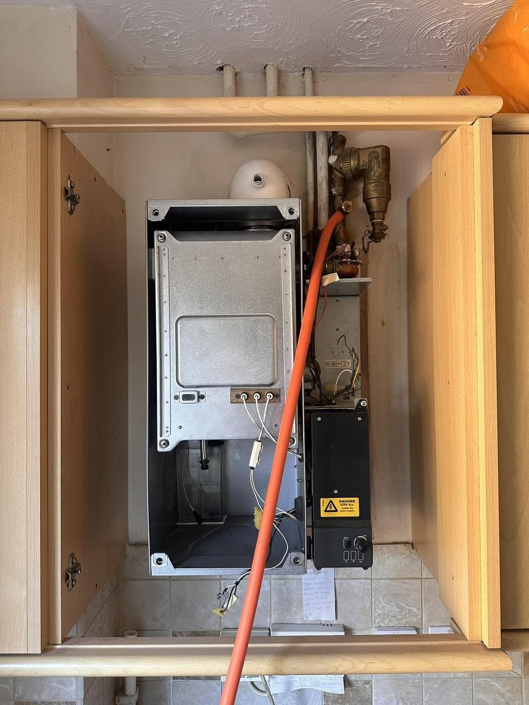 The old boiler in a kitchen cupboard with its casing off, before replacement