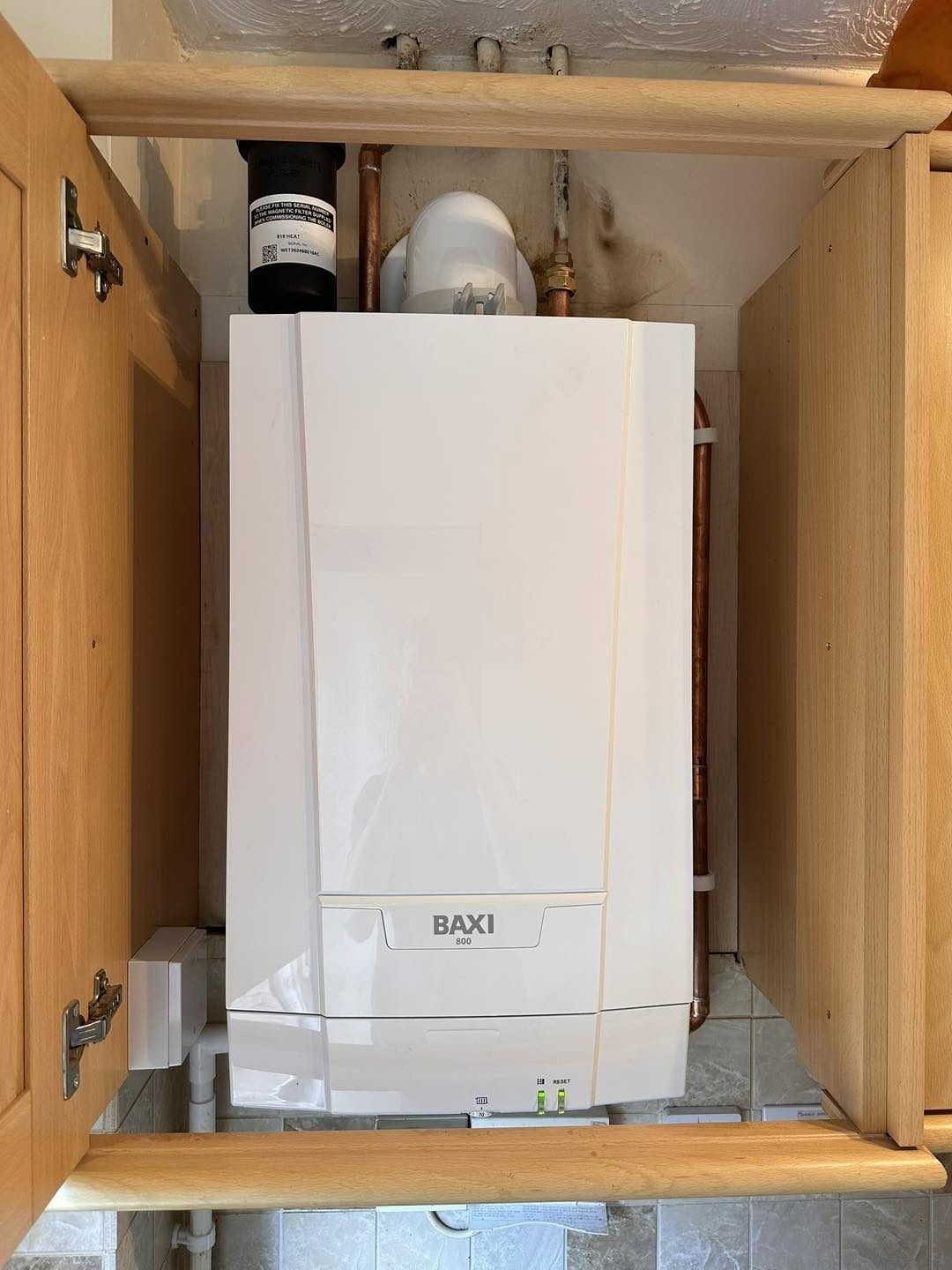 A new white Baxi combi boiler fitted in the same kitchen cupboard