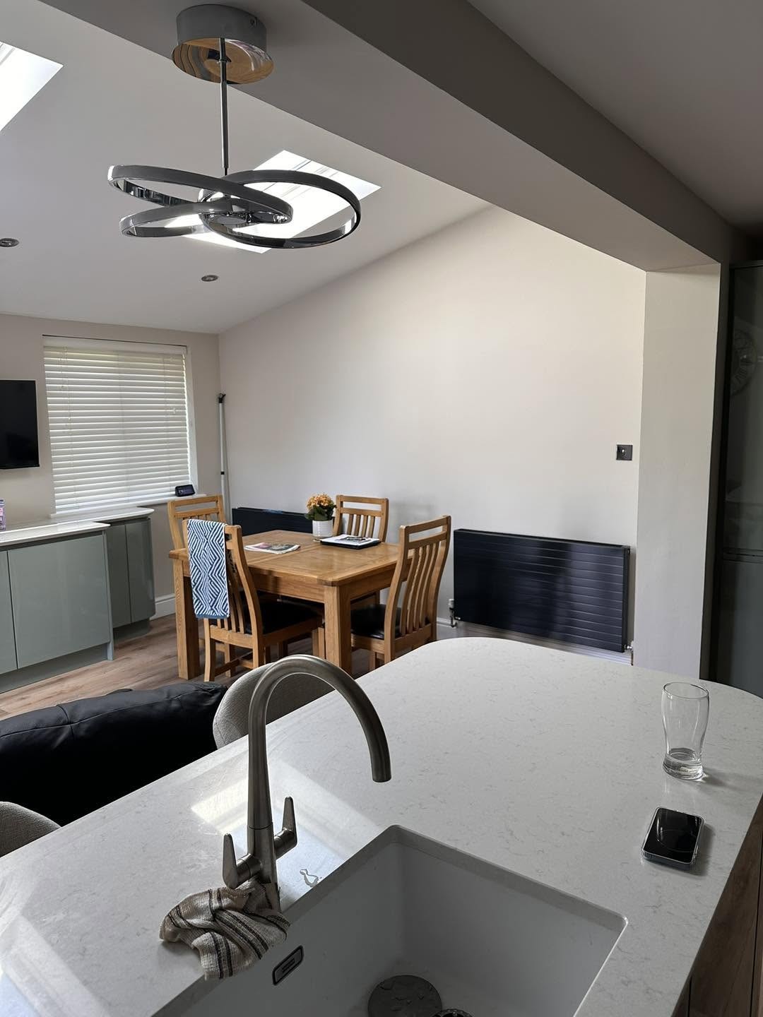 Kitchen island sink with the dining area beyond and new dark radiators under the window