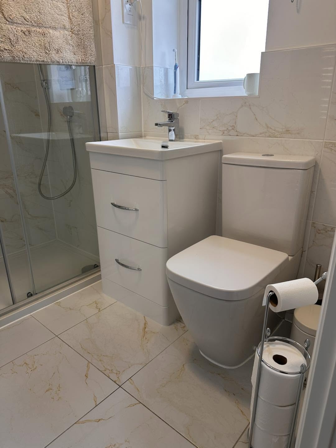 Bathroom with a white vanity unit, close coupled toilet and glass shower