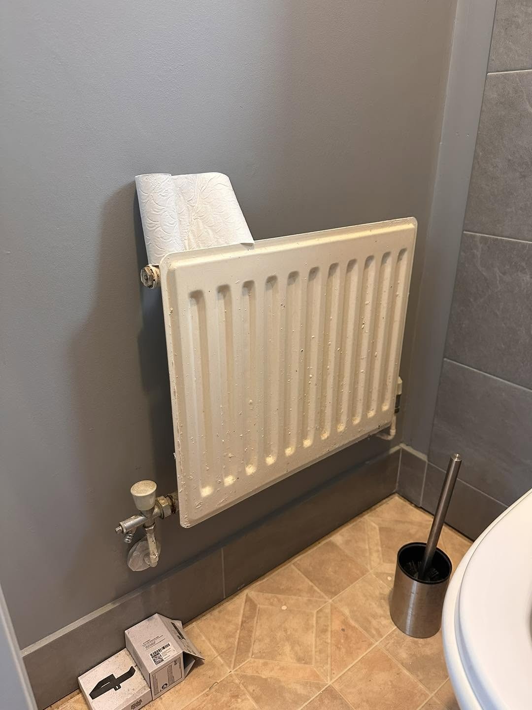 White radiator with a thermostatic valve in a grey bathroom