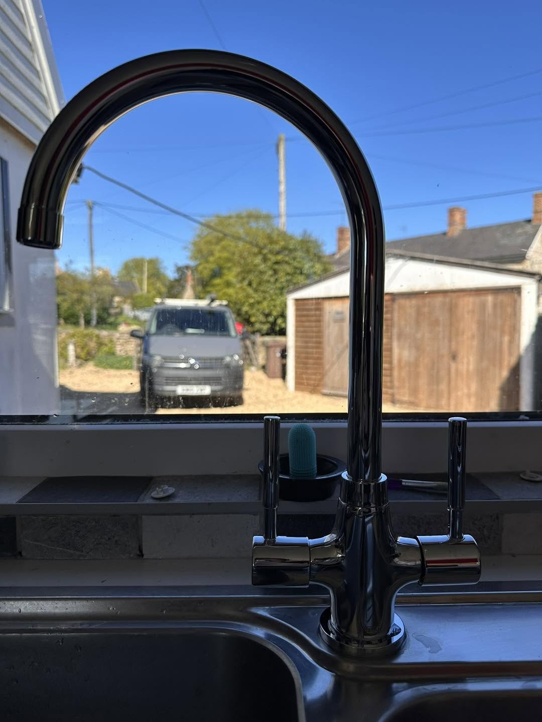 A black kitchen mixer tap fitted at a window