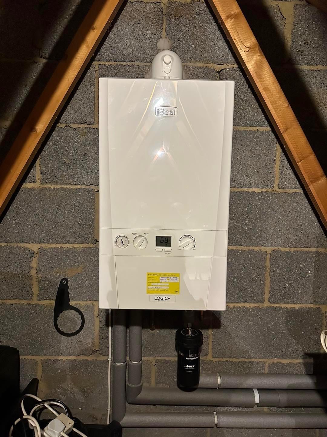 New white combi boiler fitted on a loft wall with grey condensate pipework