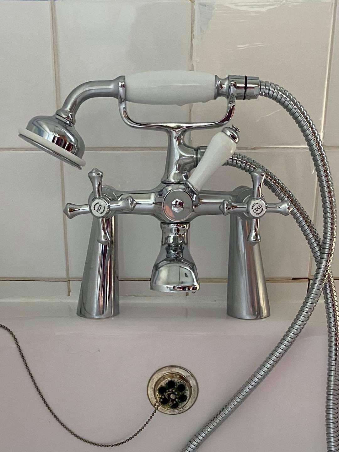 A chrome traditional bath shower mixer tap with white ceramic handles
