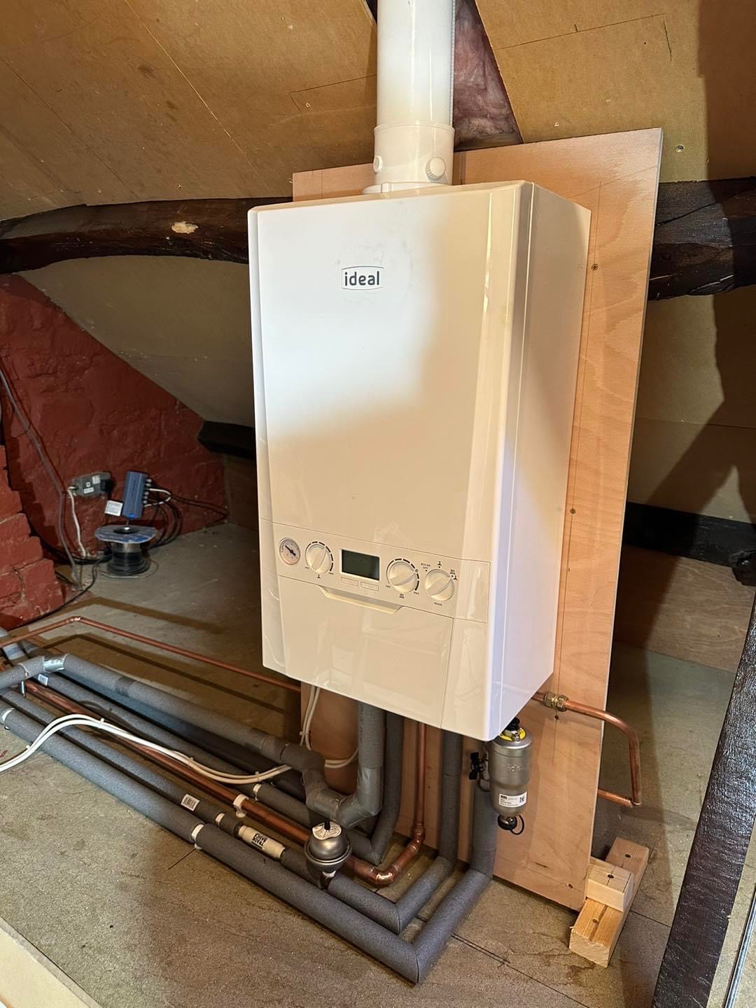 New Ideal combi boiler mounted on a board with pipework being connected