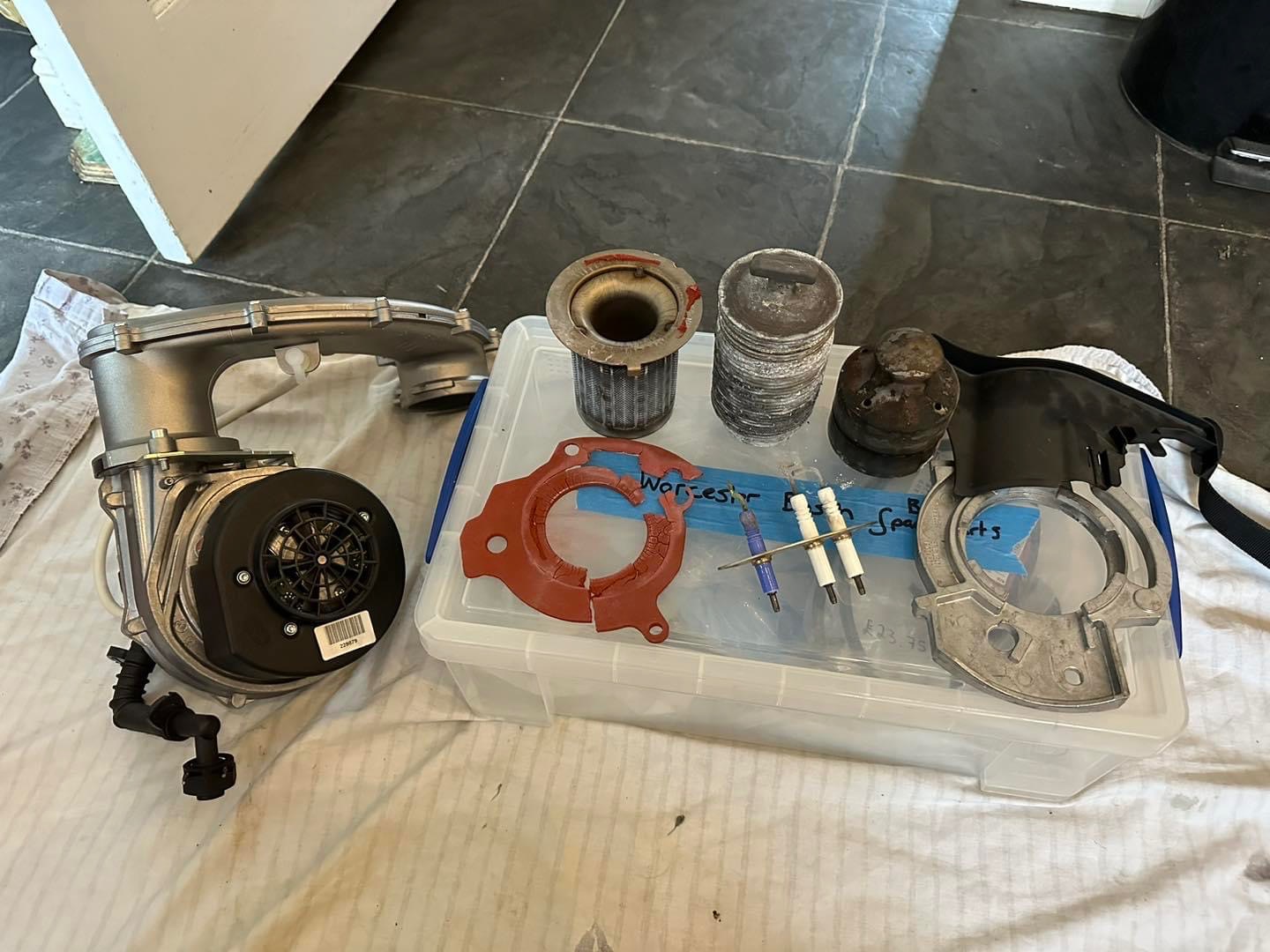 Boiler service parts laid out on a dust sheet: fan, gaskets, electrodes and burner