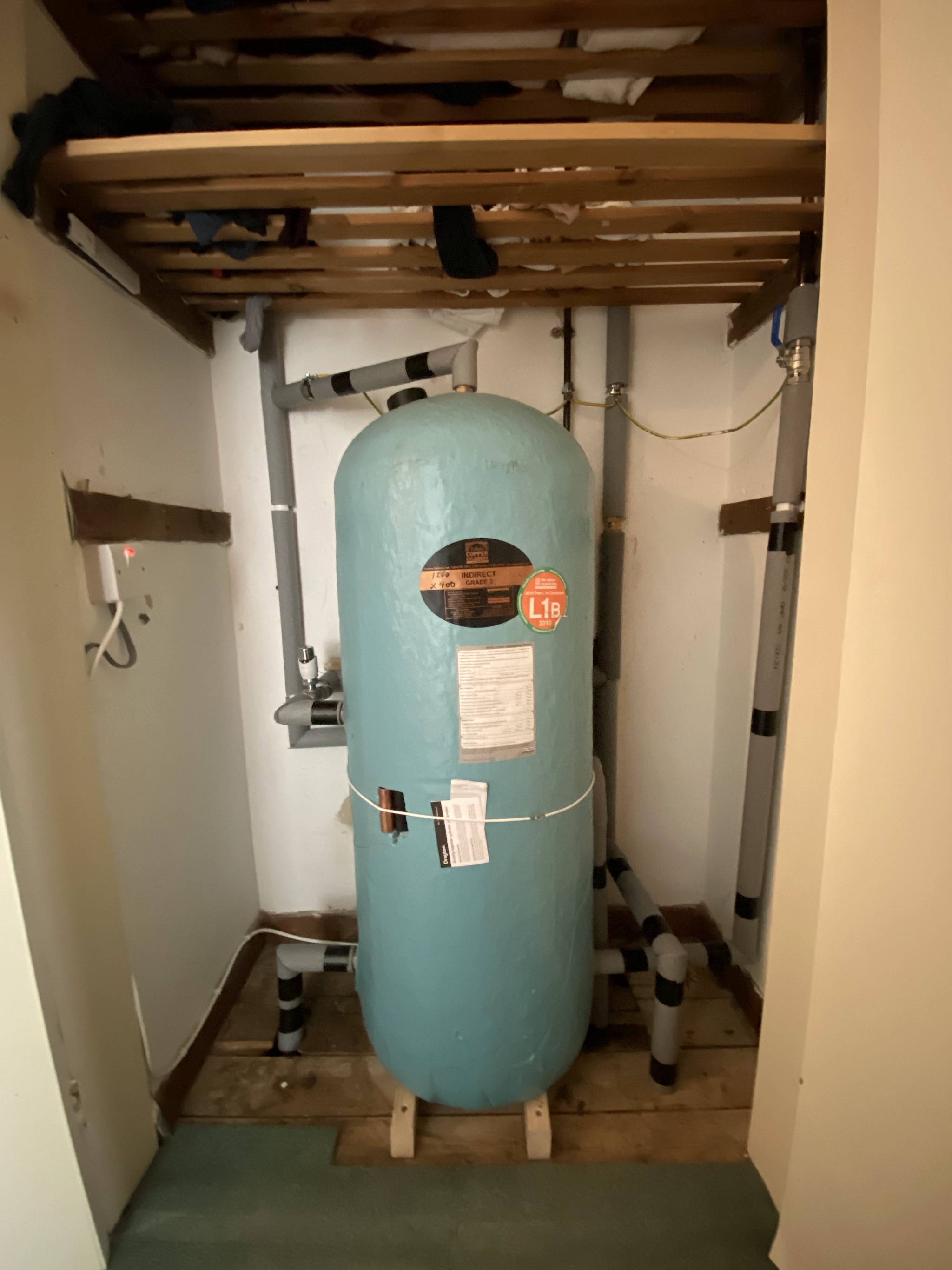 An old blue copper hot water cylinder in an airing cupboard before replacement